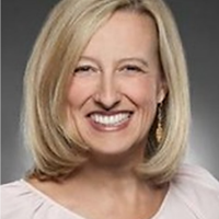 Professional headshot of a smiling blonde woman with shoulder-length hair against a gray background.