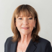Head-and-shoulders portrait of a professional woman in a dark blazer, smiling at the camera.